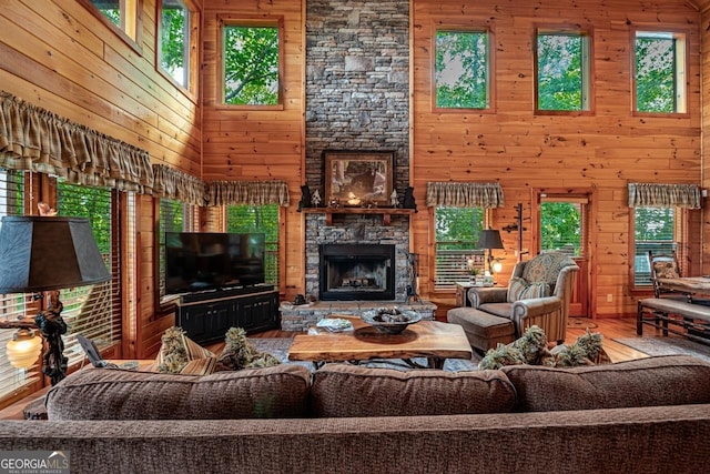 living room with wood walls, wood-type flooring, a towering ceiling, and a fireplace