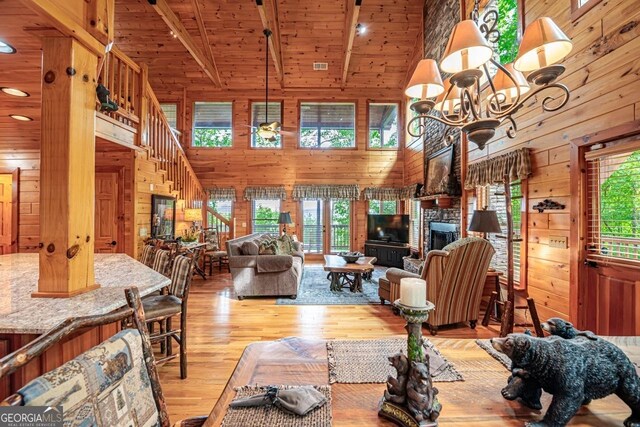 living room with wooden walls, high vaulted ceiling, light wood-type flooring, and a wealth of natural light