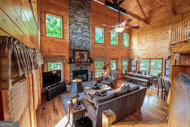 living room with a wealth of natural light, wooden walls, and high vaulted ceiling