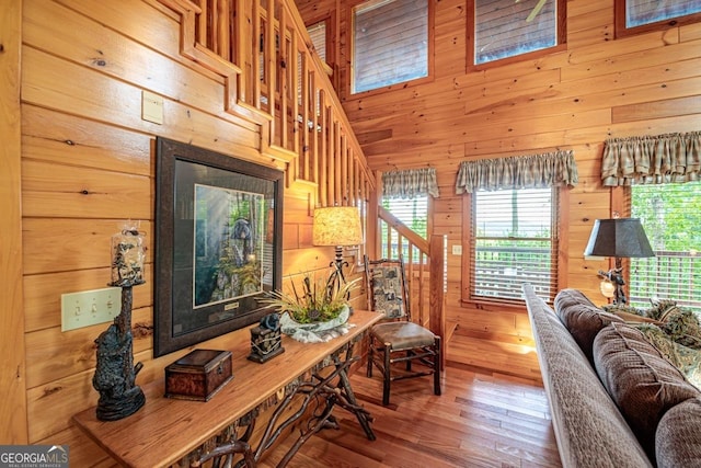 living room with wood walls, hardwood / wood-style floors, and a high ceiling