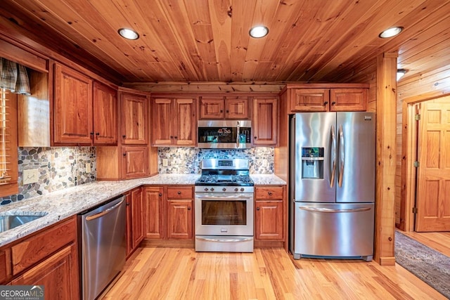 kitchen with backsplash, light stone counters, stainless steel appliances, and light wood-type flooring