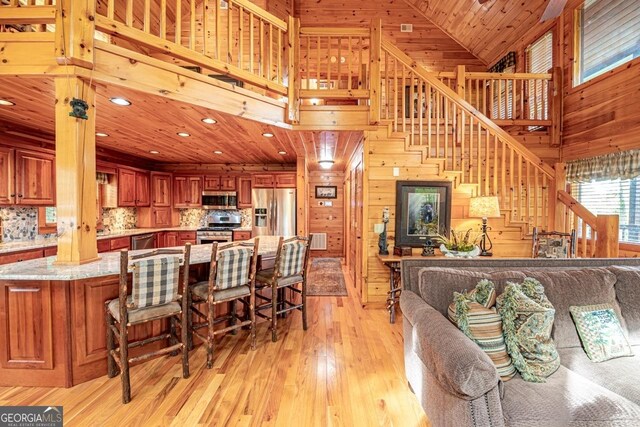 living room with high vaulted ceiling, light hardwood / wood-style flooring, wooden ceiling, and wood walls