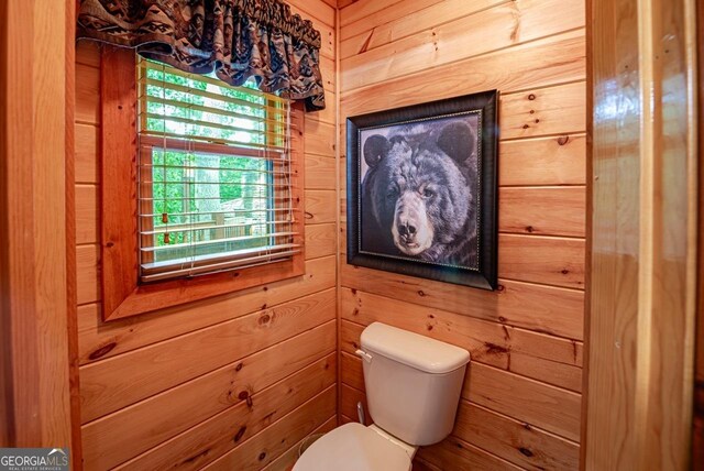 bathroom featuring wood walls and toilet