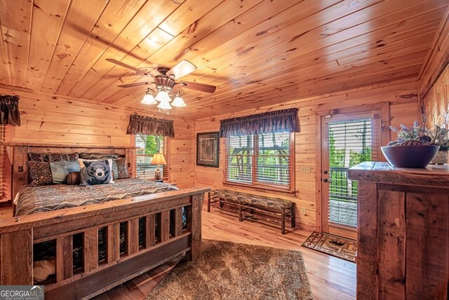 bedroom featuring wood ceiling, multiple windows, wooden walls, and wood-type flooring