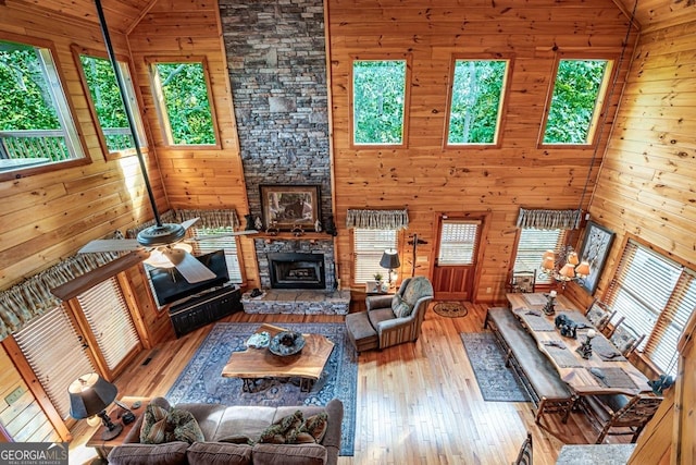 living room with light hardwood / wood-style floors, high vaulted ceiling, a wealth of natural light, and wood walls