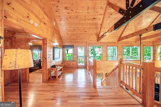 hallway featuring wooden walls, high vaulted ceiling, light hardwood / wood-style flooring, wooden ceiling, and beamed ceiling