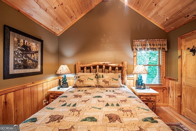 bedroom featuring hardwood / wood-style floors, wooden ceiling, wooden walls, vaulted ceiling, and ornamental molding