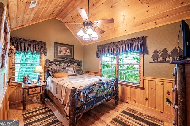 bedroom with ceiling fan, hardwood / wood-style flooring, wooden ceiling, lofted ceiling, and wood walls