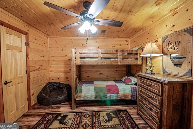 bedroom with wooden walls, hardwood / wood-style floors, ceiling fan, and wooden ceiling