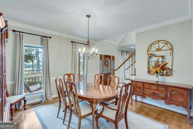 dining area with light wood-type flooring, crown molding, and an inviting chandelier