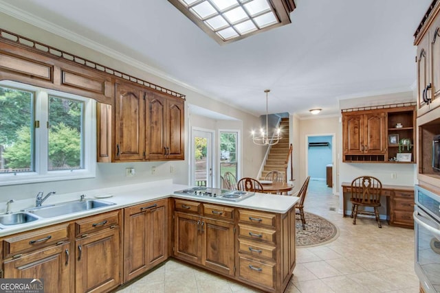 kitchen featuring sink, white gas stovetop, kitchen peninsula, hanging light fixtures, and an inviting chandelier