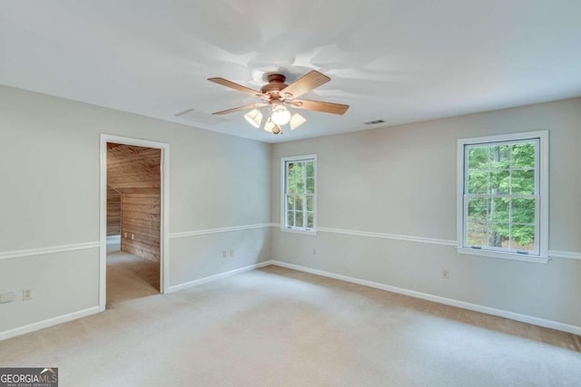 unfurnished room featuring ceiling fan, a wealth of natural light, and light colored carpet