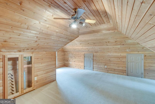 additional living space with lofted ceiling, wooden ceiling, wooden walls, and ceiling fan