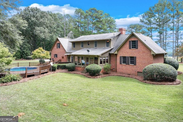 back of property with a lawn and a swimming pool side deck