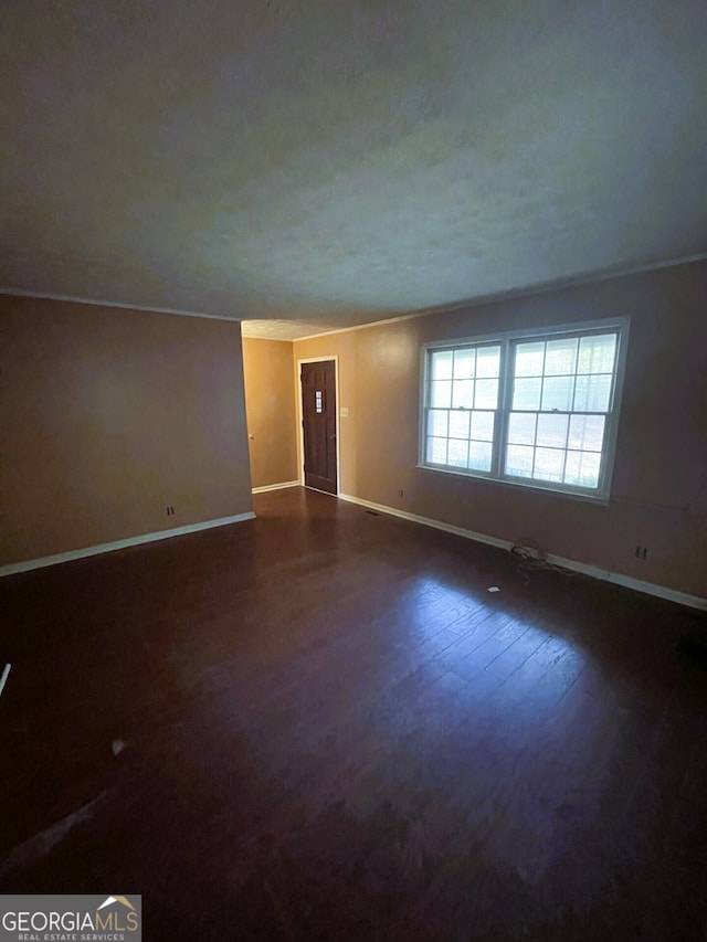 unfurnished room featuring dark wood-type flooring and crown molding