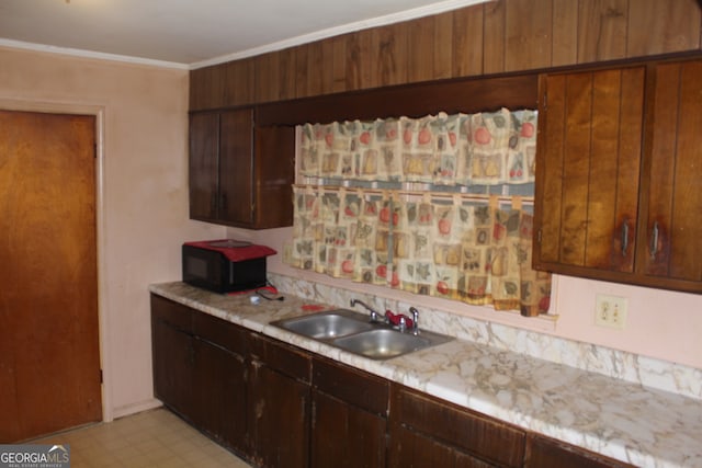 kitchen with sink, dark brown cabinets, and crown molding