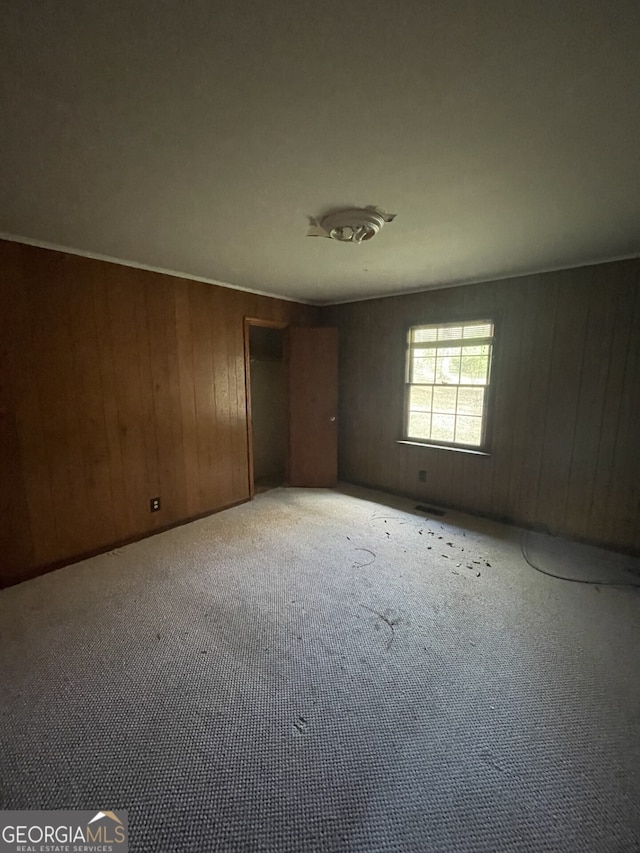 unfurnished bedroom featuring wooden walls and light carpet