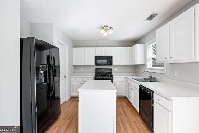 kitchen with light wood-type flooring, a center island, sink, and black appliances