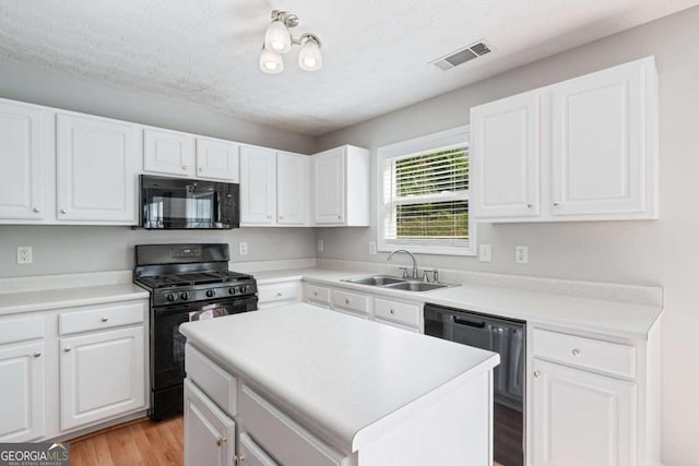 kitchen featuring black appliances, a center island, white cabinets, sink, and light hardwood / wood-style floors