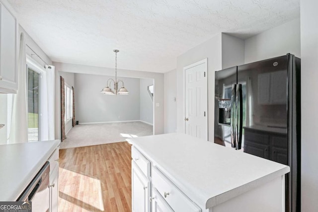 kitchen featuring a kitchen island, black fridge, light hardwood / wood-style flooring, and white cabinetry