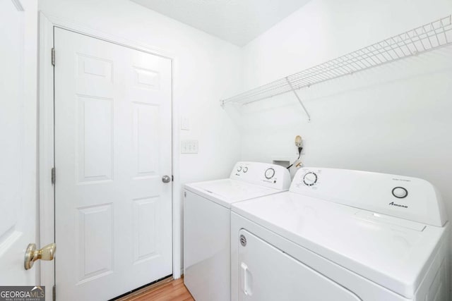 clothes washing area with washing machine and dryer and light hardwood / wood-style floors