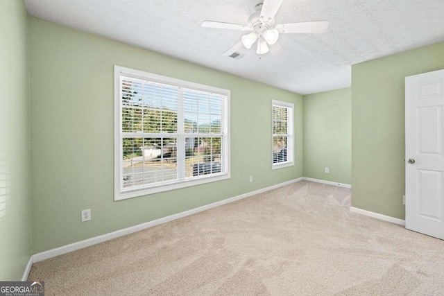 spare room with ceiling fan, light colored carpet, and a textured ceiling