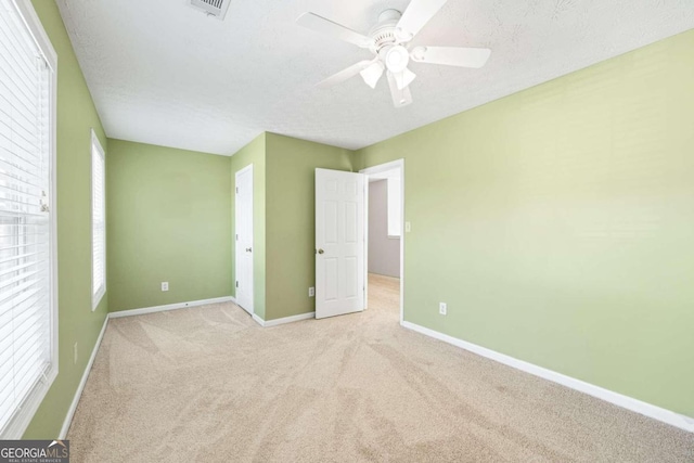 unfurnished bedroom with light carpet, a textured ceiling, and ceiling fan