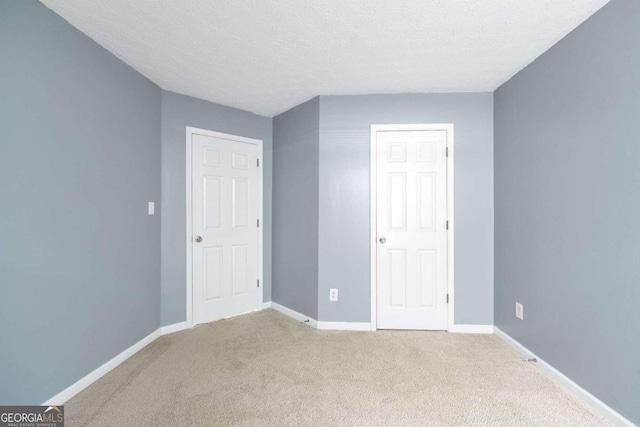 unfurnished bedroom with light carpet and a textured ceiling