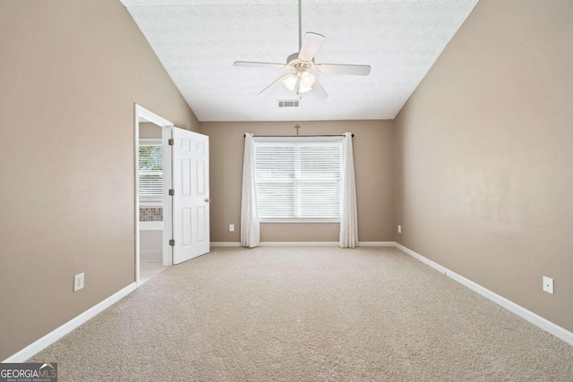 unfurnished room featuring lofted ceiling, ceiling fan, carpet, and a textured ceiling