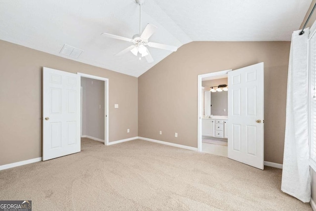 unfurnished bedroom with lofted ceiling, light carpet, ensuite bathroom, and ceiling fan