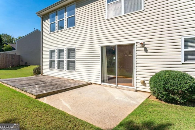 back of property with a wooden deck and a lawn