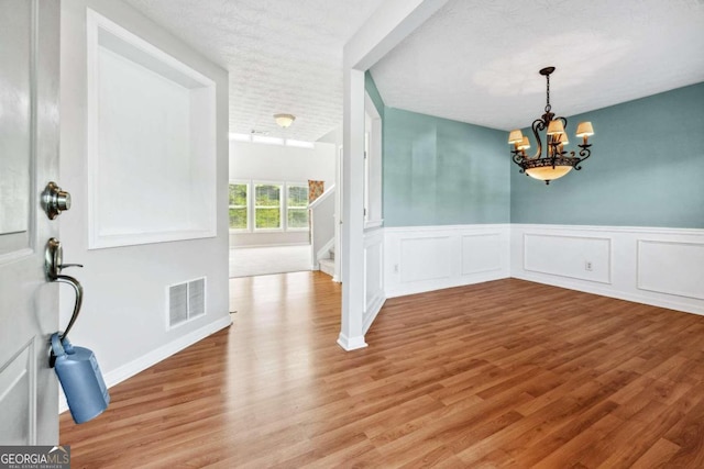 foyer featuring a chandelier, light hardwood / wood-style flooring, and a textured ceiling