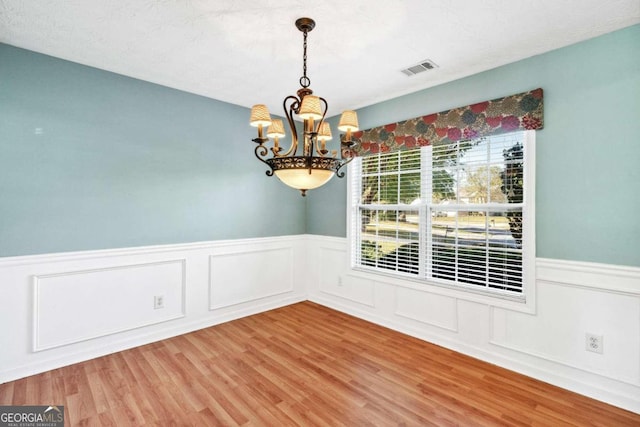 empty room featuring a chandelier and wood-type flooring