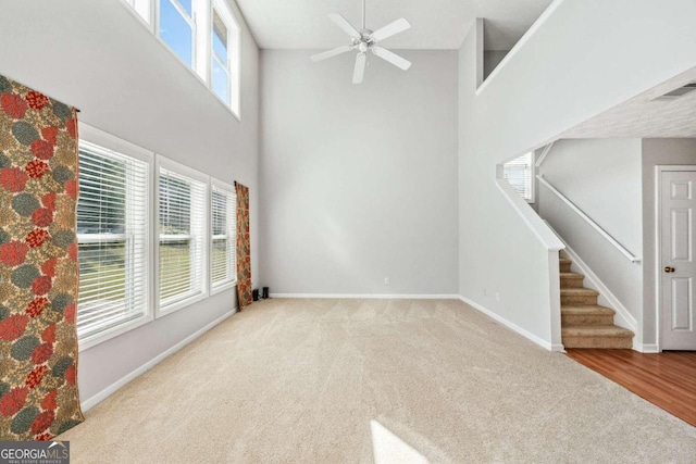 unfurnished living room with a high ceiling, a wealth of natural light, and light carpet