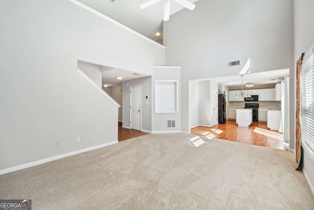 unfurnished living room with high vaulted ceiling, light wood-type flooring, and ceiling fan