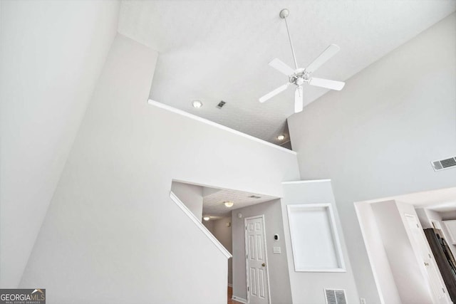 stairway featuring ceiling fan, a textured ceiling, and high vaulted ceiling