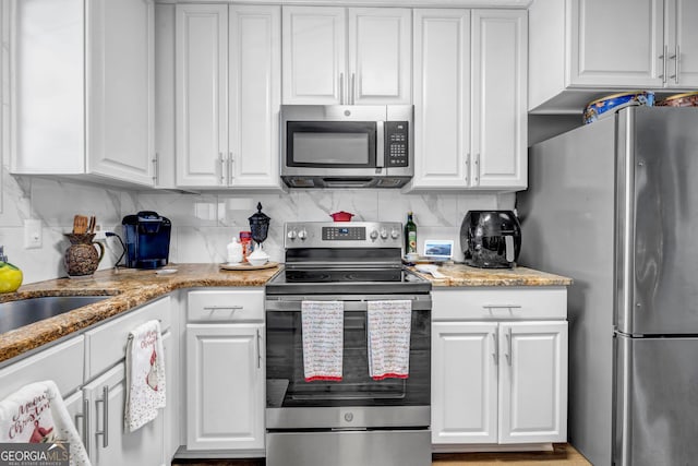 kitchen with decorative backsplash, light stone counters, white cabinetry, and appliances with stainless steel finishes