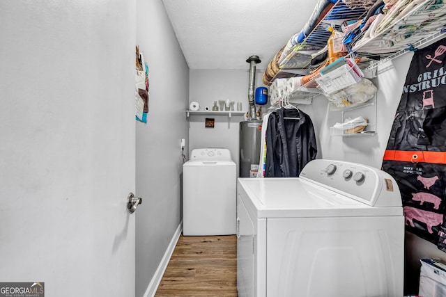 washroom featuring light hardwood / wood-style flooring, independent washer and dryer, a textured ceiling, and water heater