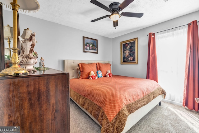 bedroom with ceiling fan, light colored carpet, and a textured ceiling