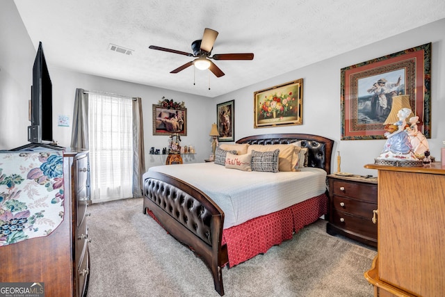 carpeted bedroom featuring ceiling fan and a textured ceiling