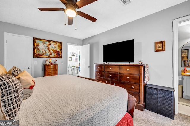 bedroom featuring ensuite bath, ceiling fan, and light carpet