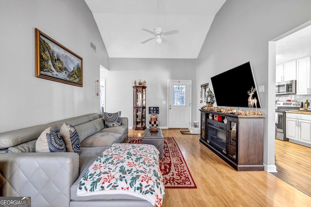 living room featuring ceiling fan, high vaulted ceiling, and light wood-type flooring