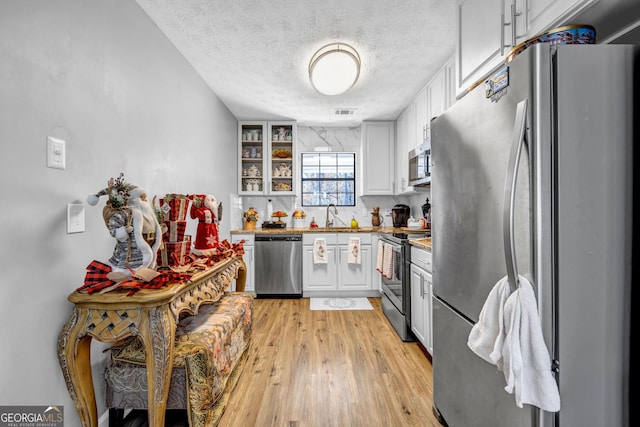 kitchen with sink, white cabinets, a textured ceiling, and appliances with stainless steel finishes