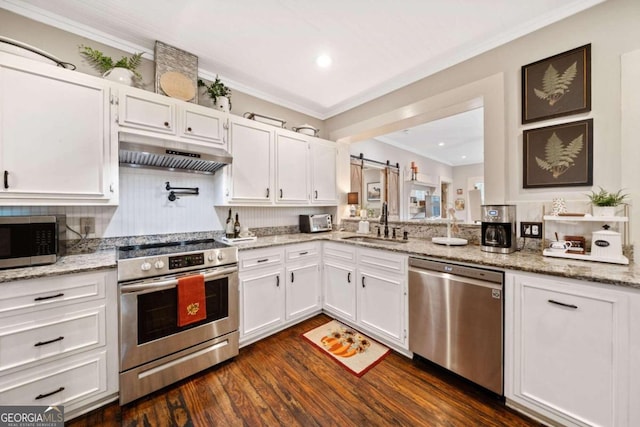 kitchen featuring sink, white cabinetry, appliances with stainless steel finishes, dark hardwood / wood-style floors, and a barn door