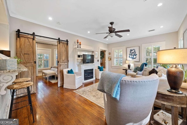 living room with ceiling fan, dark hardwood / wood-style floors, ornamental molding, and a healthy amount of sunlight