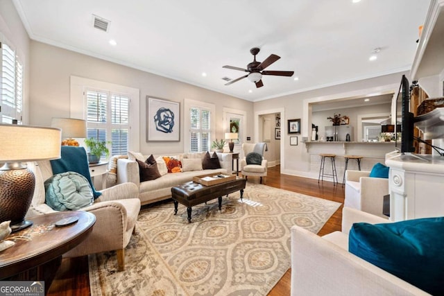 living room featuring ceiling fan, light hardwood / wood-style flooring, ornamental molding, and a wealth of natural light