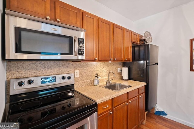 kitchen with hardwood / wood-style flooring, sink, stainless steel appliances, and tasteful backsplash