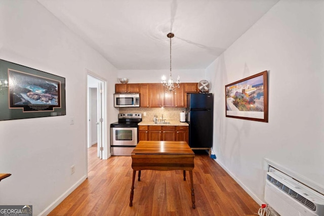 kitchen with tasteful backsplash, light hardwood / wood-style floors, hanging light fixtures, a chandelier, and appliances with stainless steel finishes