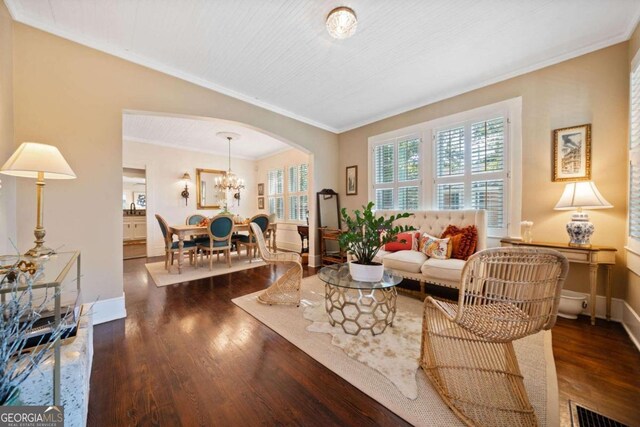 living room with ornamental molding, a chandelier, and dark hardwood / wood-style flooring