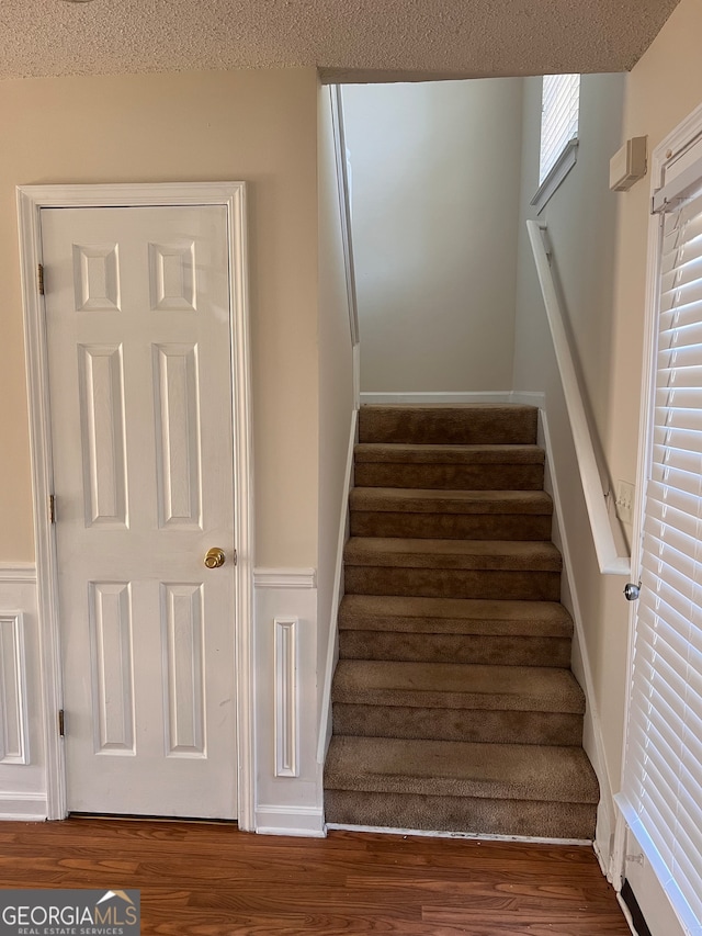 staircase with wood-type flooring and a textured ceiling